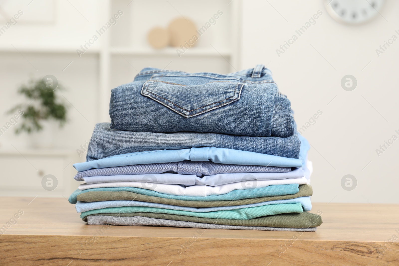 Photo of Stack of clothes on wooden table indoors