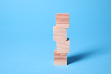 Photo of Many blank wooden cubes on light blue background, space for text