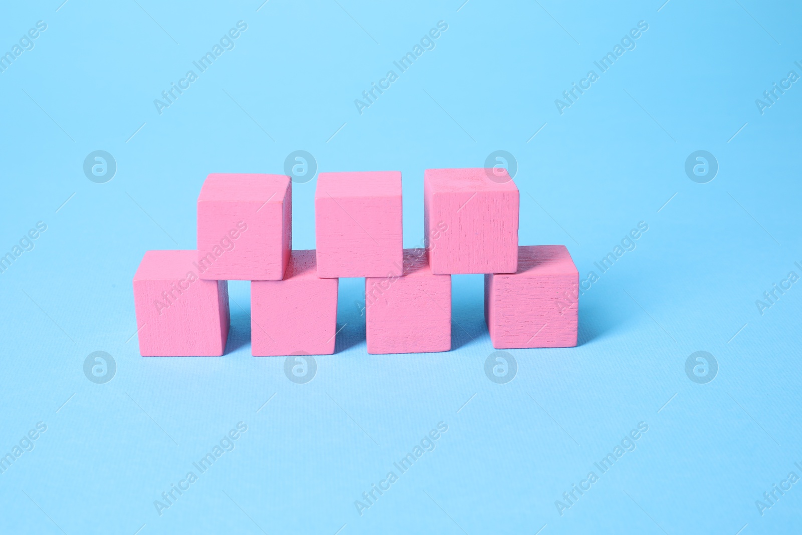 Photo of Many blank pink cubes on light blue background