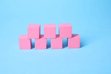 Photo of Many blank pink cubes on light blue background