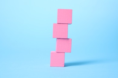 Photo of Many blank pink cubes on light blue background