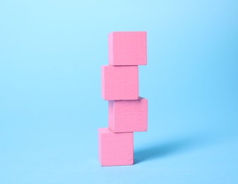 Photo of Many blank pink cubes on light blue background