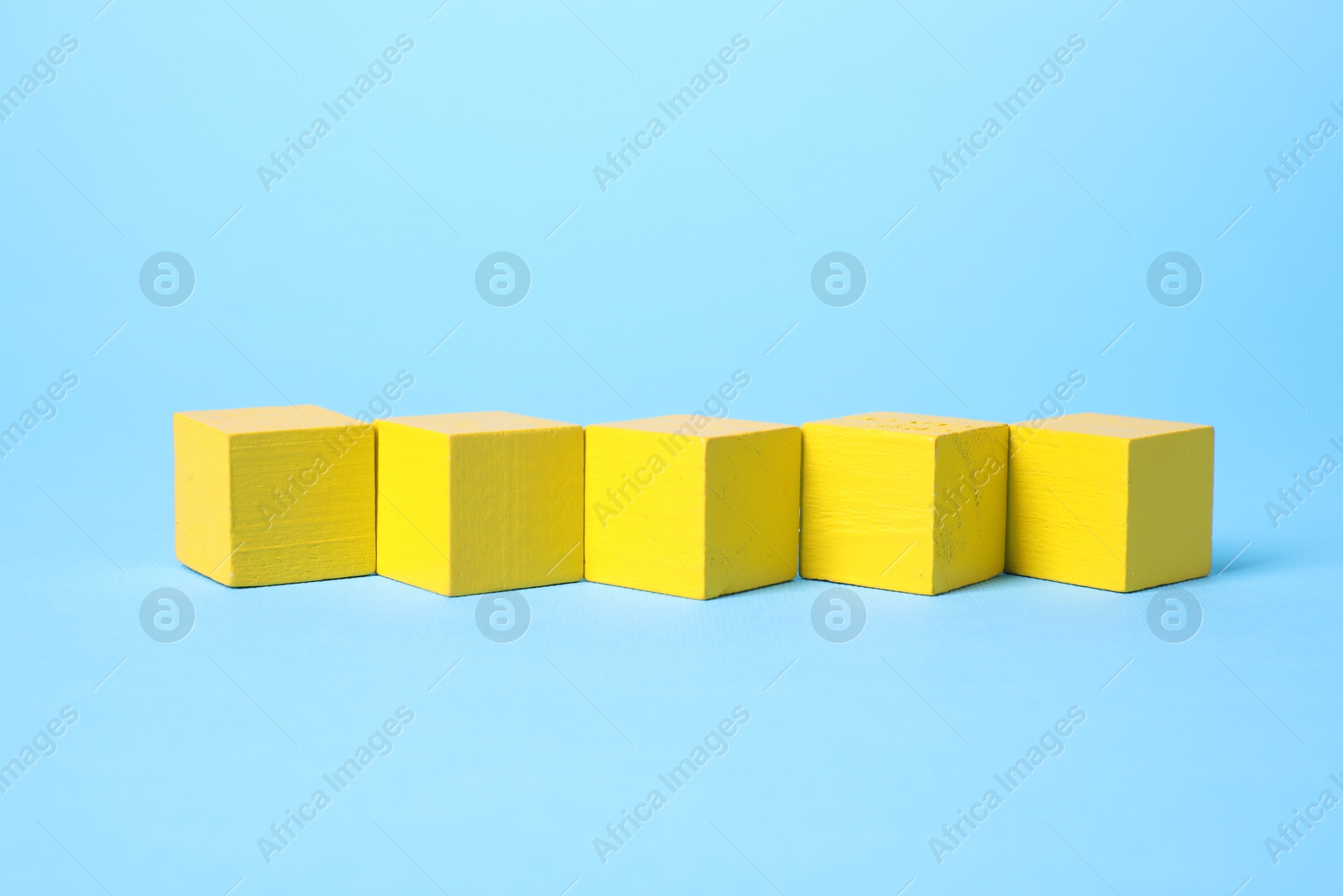 Photo of Blank yellow cubes on light blue background