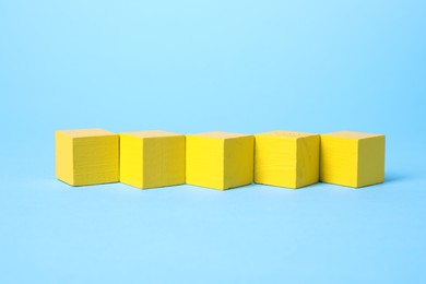 Photo of Blank yellow cubes on light blue background