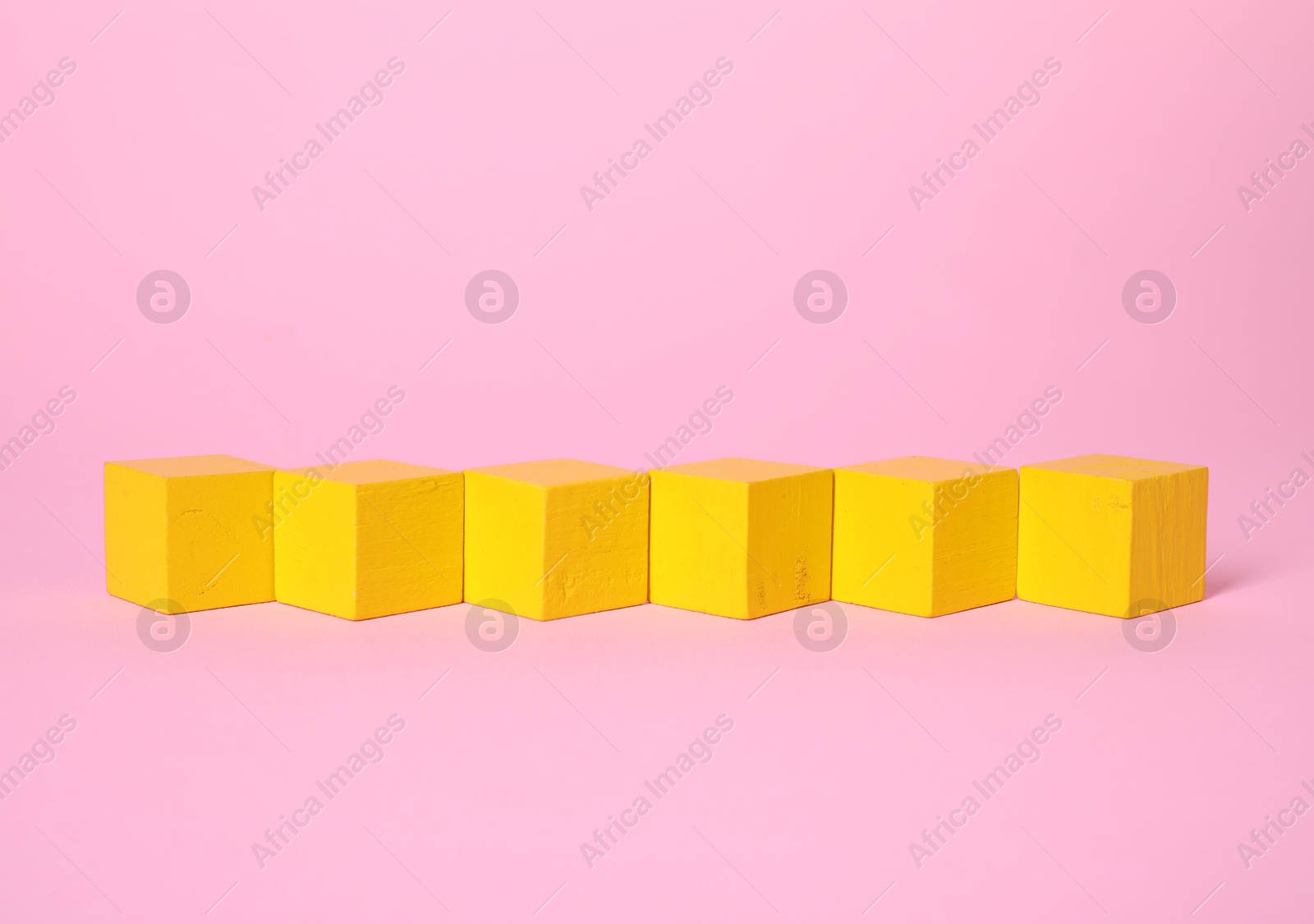 Photo of Many blank yellow cubes on pink background