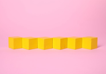 Photo of Many blank yellow cubes on pink background