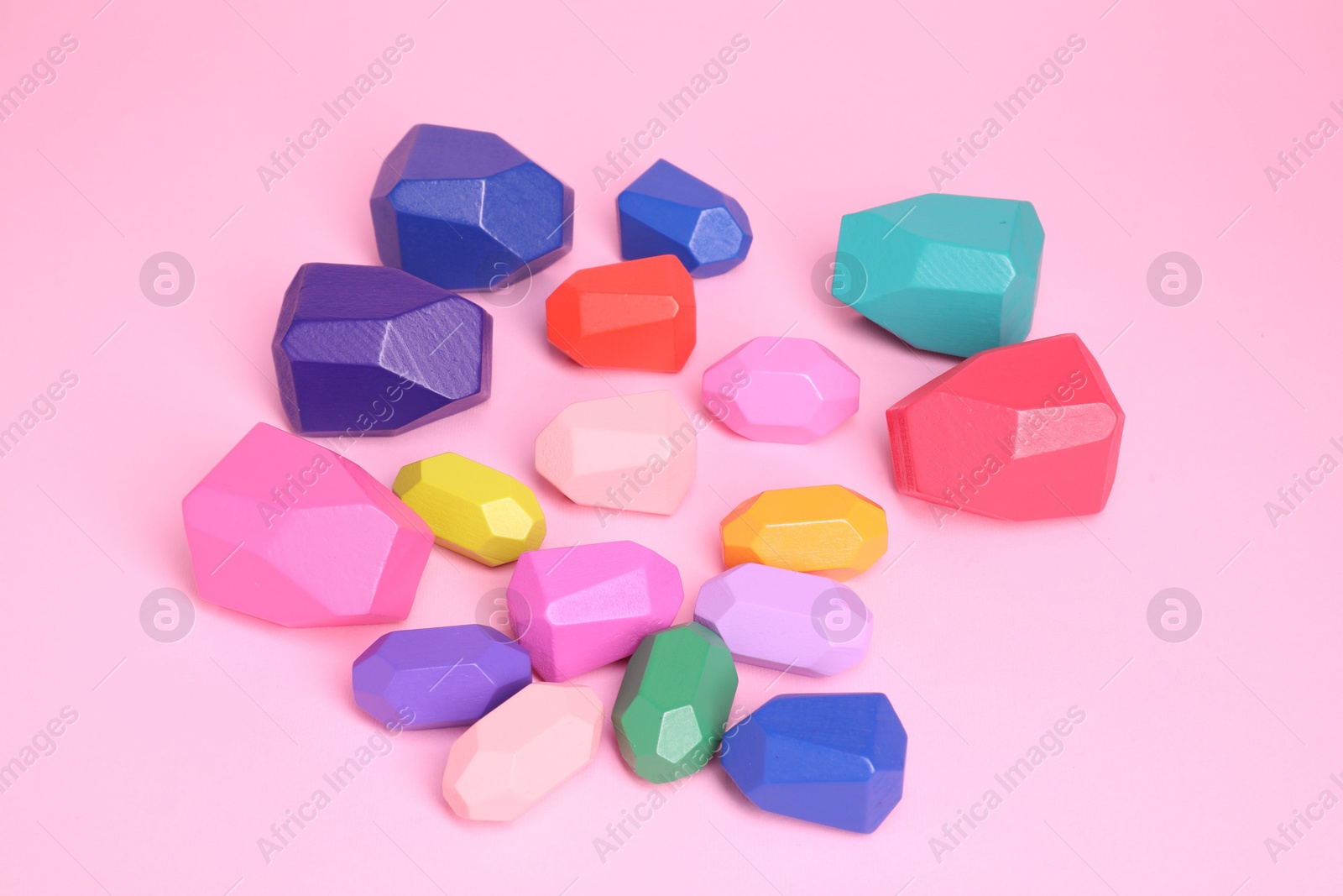 Photo of Many colorful balancing stones on pink background, above view