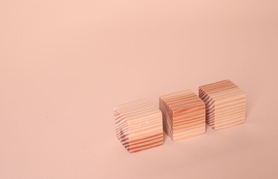 Three blank wooden cubes on beige background, space for text