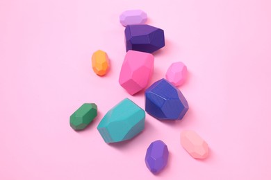 Photo of Many colorful balancing stones on pink background, top view