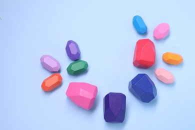 Photo of Many colorful balancing stones on light blue background, top view