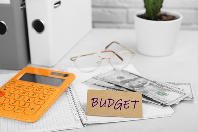 Image of Card with word Budget, calculator, glasses and money on white table