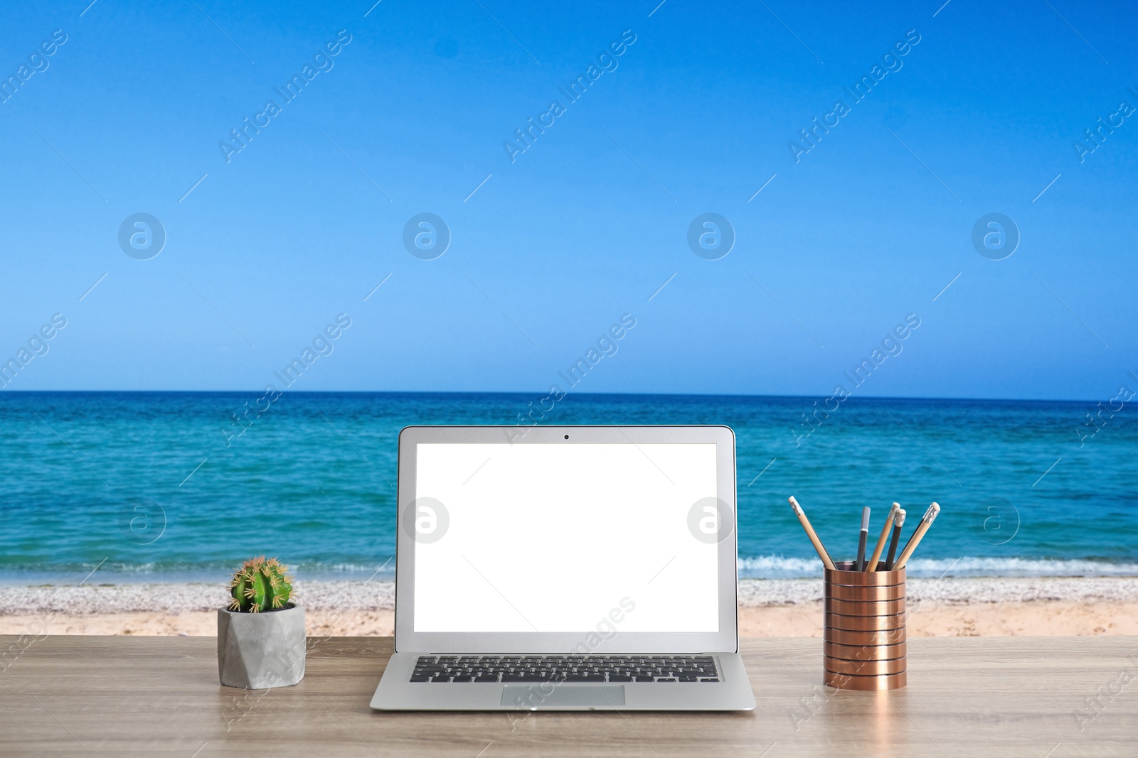 Image of Workplace at beach, distant office. Table with laptop on sandy seashore. Mockup for design