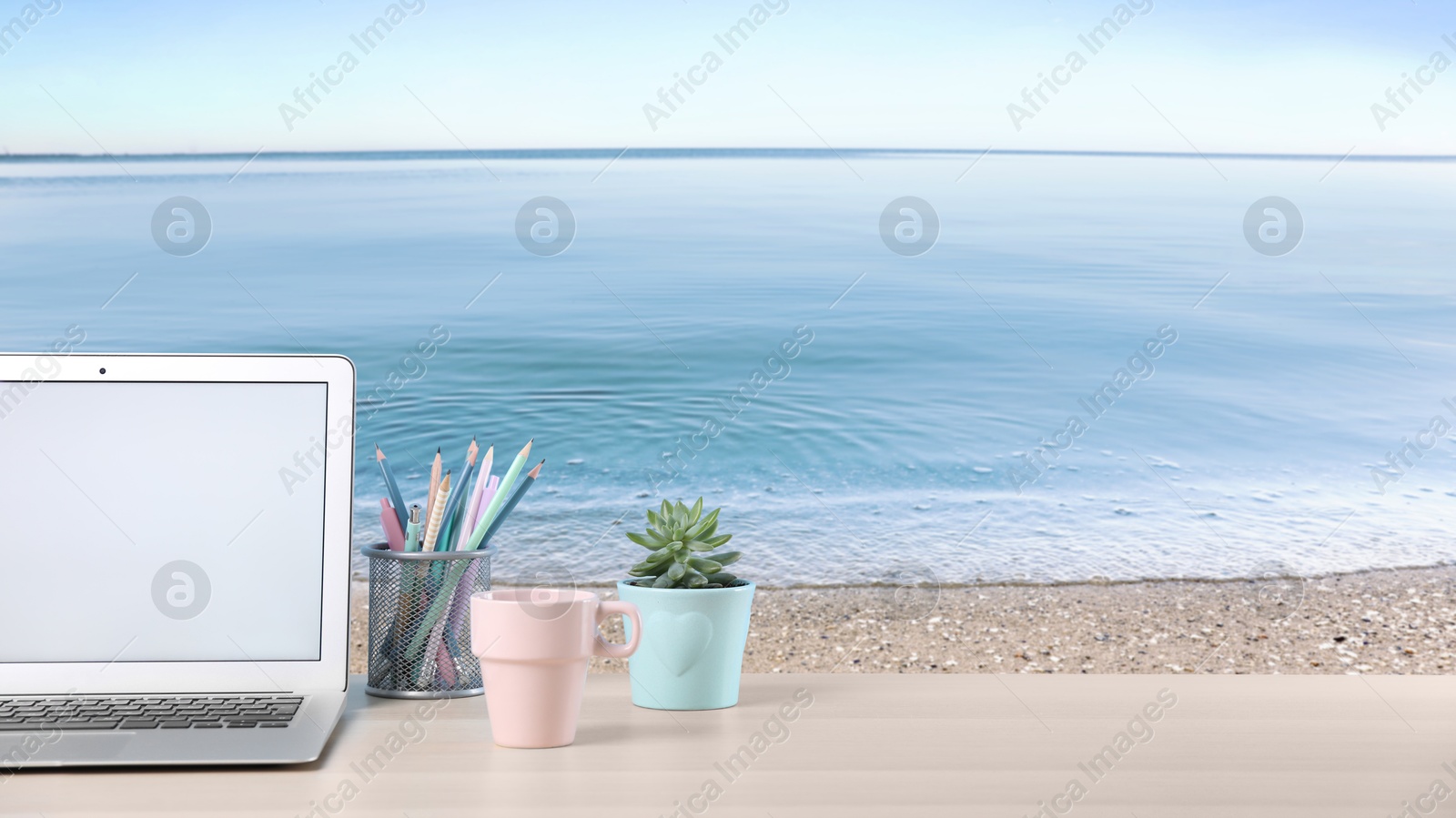 Image of Workplace at beach, distant office. Table with laptop on sandy seashore. Banner design with space for text