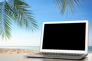 Image of Workplace at beach, distant office. Table with laptop on sandy seashore. Mockup for design