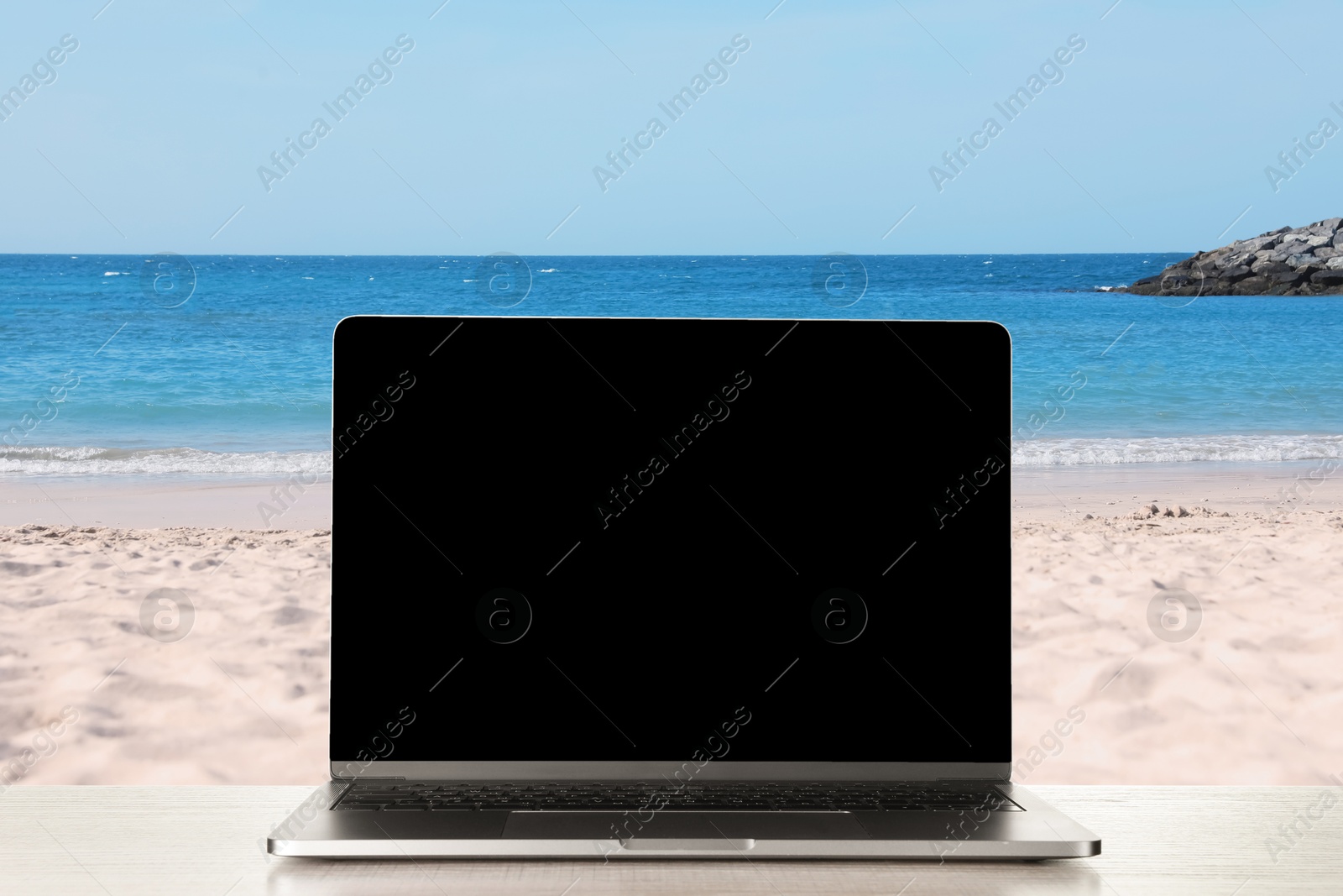 Image of Workplace at beach, distant office. Table with laptop on sandy seashore. Mockup for design