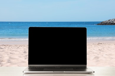 Image of Workplace at beach, distant office. Table with laptop on sandy seashore. Mockup for design