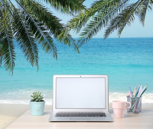 Workplace at beach, distant office. Table with laptop on sandy seashore. Mockup for design