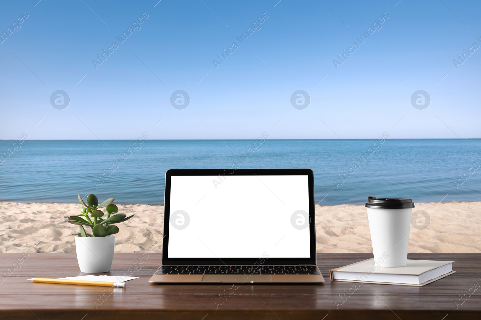 Image of Workplace at beach, distant office. Table with laptop on sandy seashore. Mockup for design