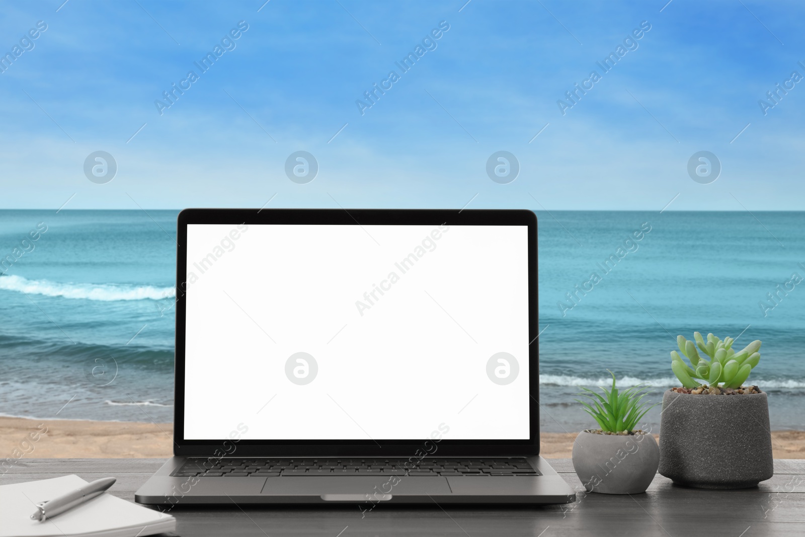 Image of Workplace at beach, distant office. Table with laptop on sandy seashore. Mockup for design