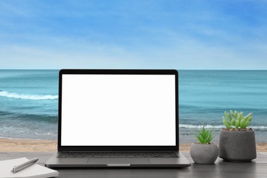 Image of Workplace at beach, distant office. Table with laptop on sandy seashore. Mockup for design