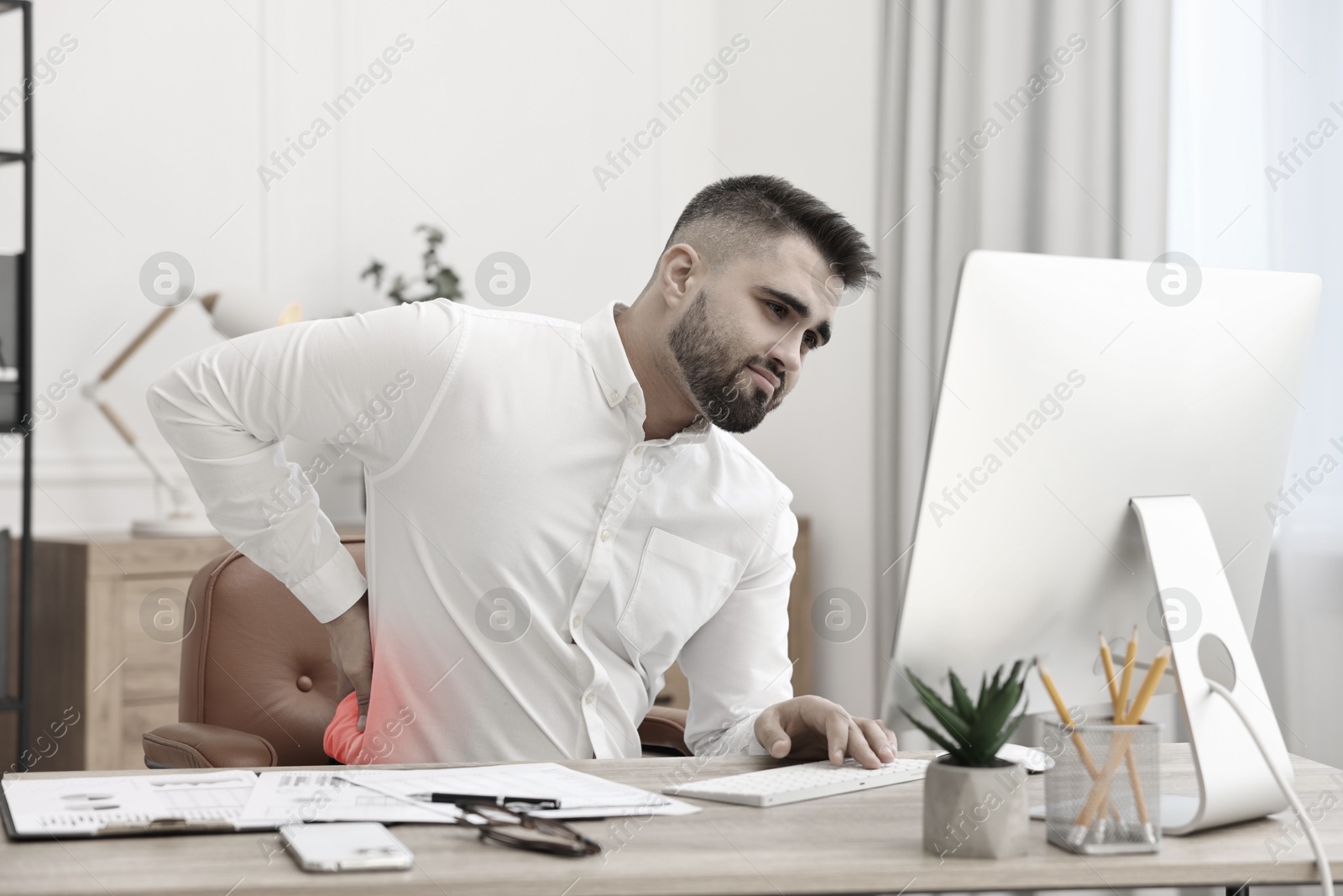 Image of Man suffering from backache due to poor posture at workplace