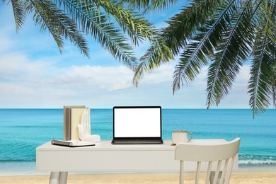 Image of Workplace at beach, distant office. Table with laptop and chair on sandy seashore. Mockup for design