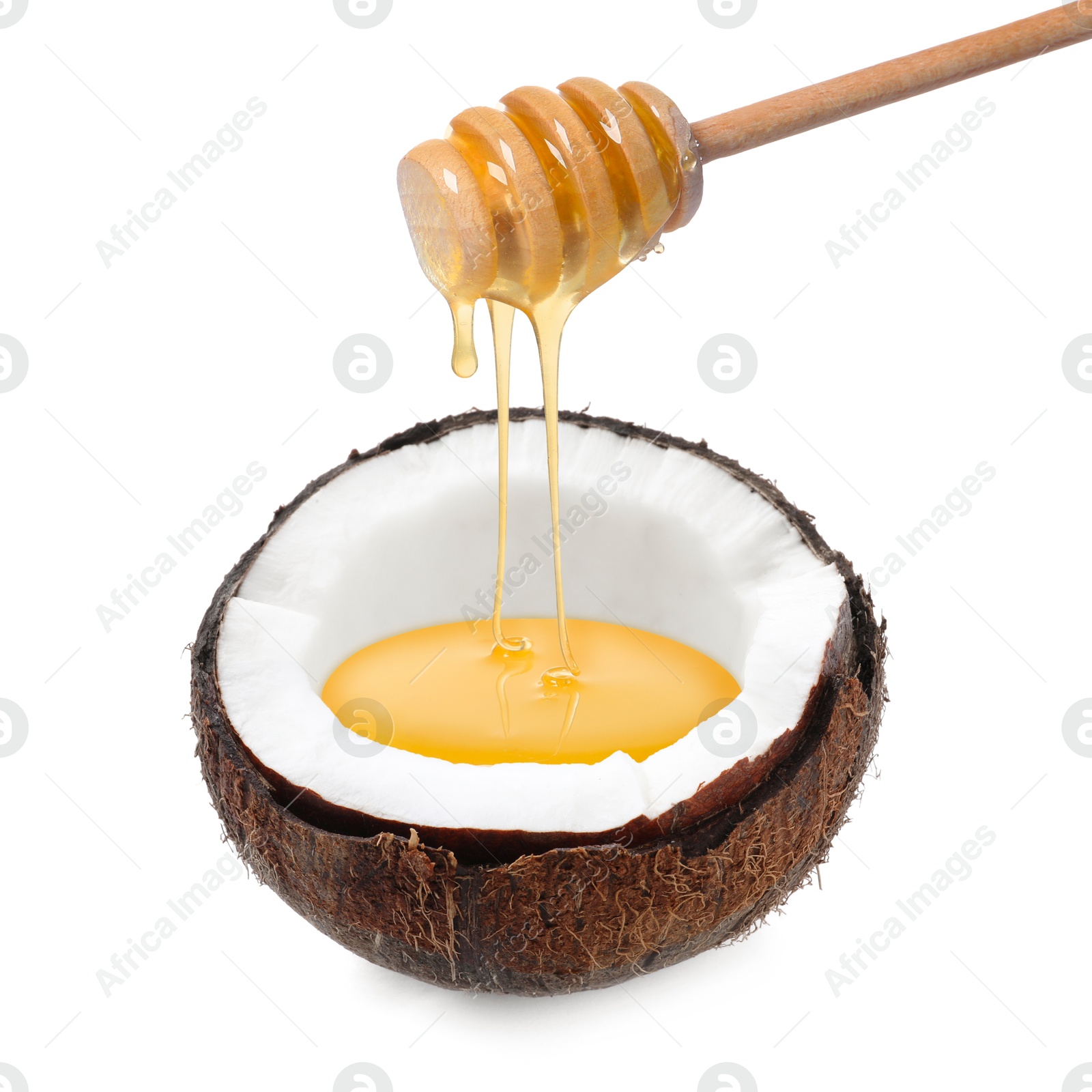 Image of Honey dripping from wooden dipper into coconut isolated on white