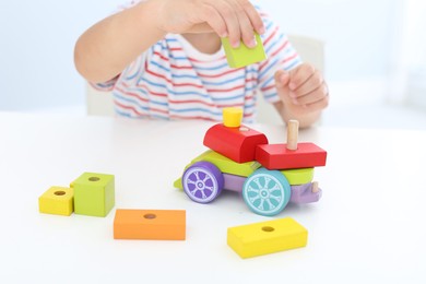 Little boy playing with toy at white table, closeup