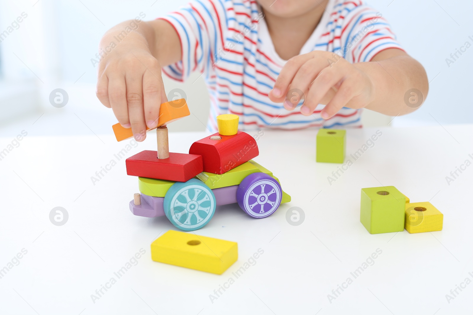 Photo of Little boy playing with toy at white table, closeup