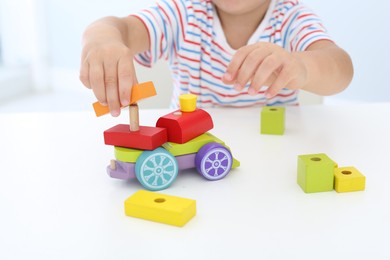 Photo of Little boy playing with toy at white table, closeup