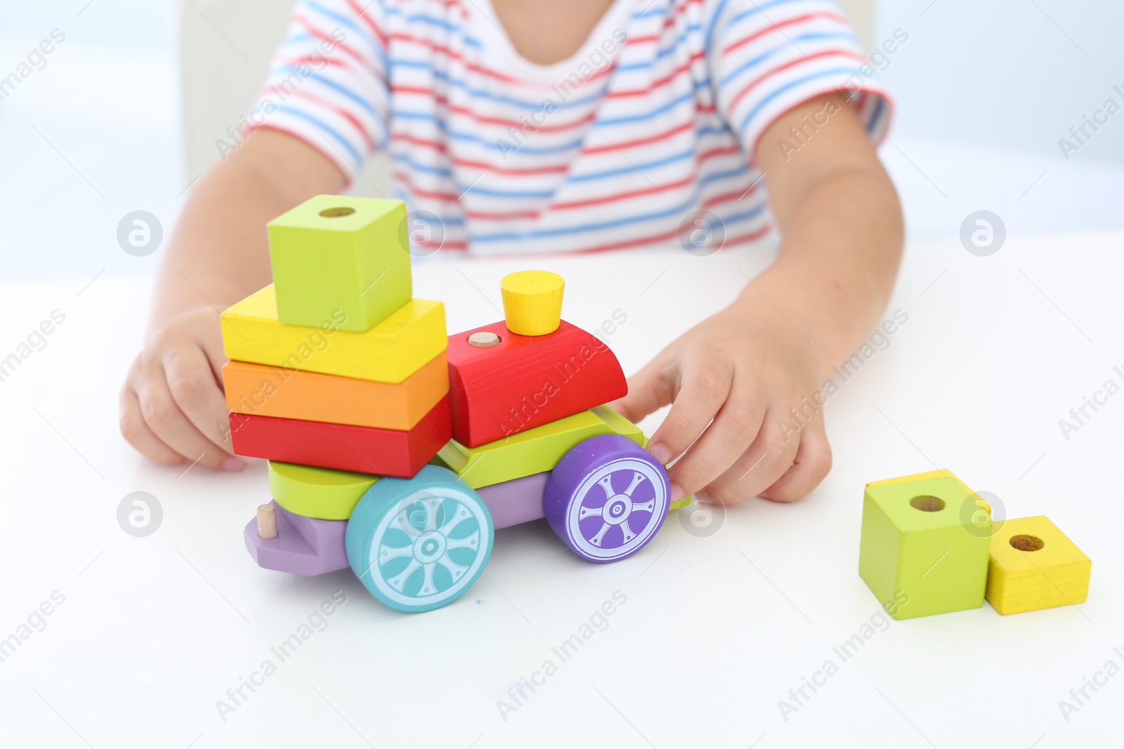 Photo of Little boy playing with toy at white table, closeup