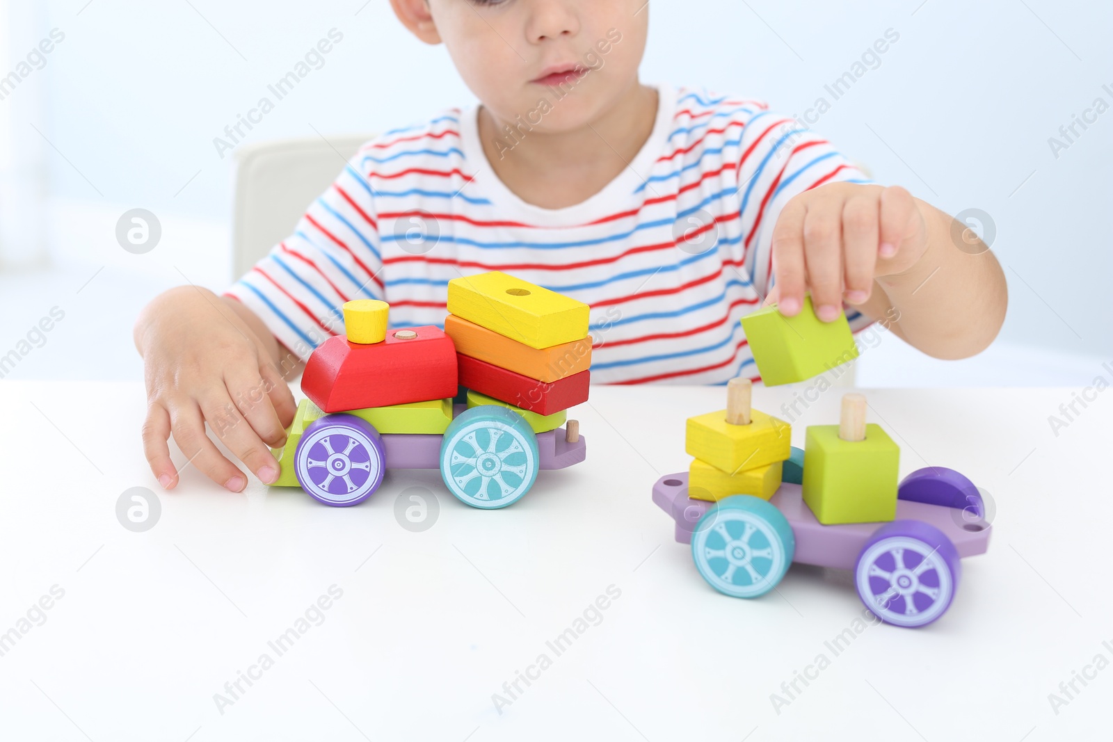 Photo of Little boy playing with toy at white table, closeup