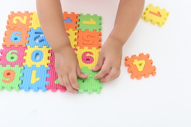 Little girl playing with colorful puzzles at white table, closeup. Educational toy