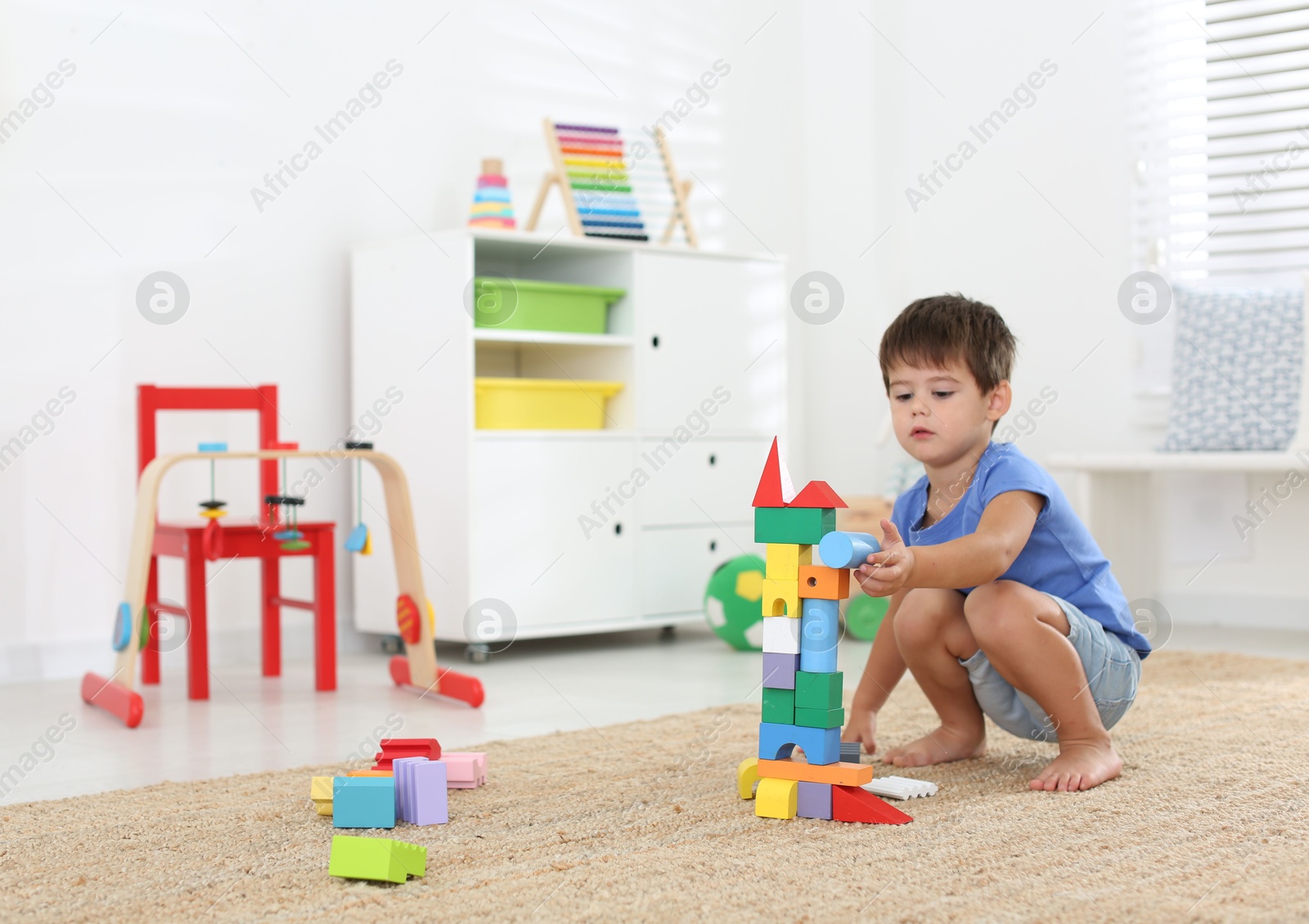 Photo of Cute little boy playing with colorful blocks on floor at home. Educational toy