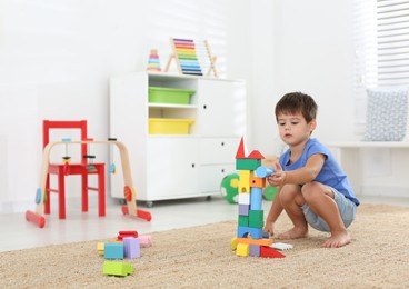 Cute little boy playing with colorful blocks on floor at home. Educational toy