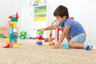 Cute little boy playing with colorful blocks on floor at home. Educational toy