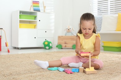 Photo of Cute little girl playing with toy on floor at home, space for text