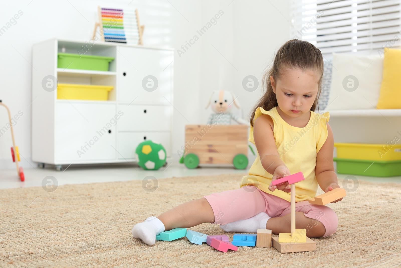 Photo of Cute little girl playing with toy on floor at home, space for text