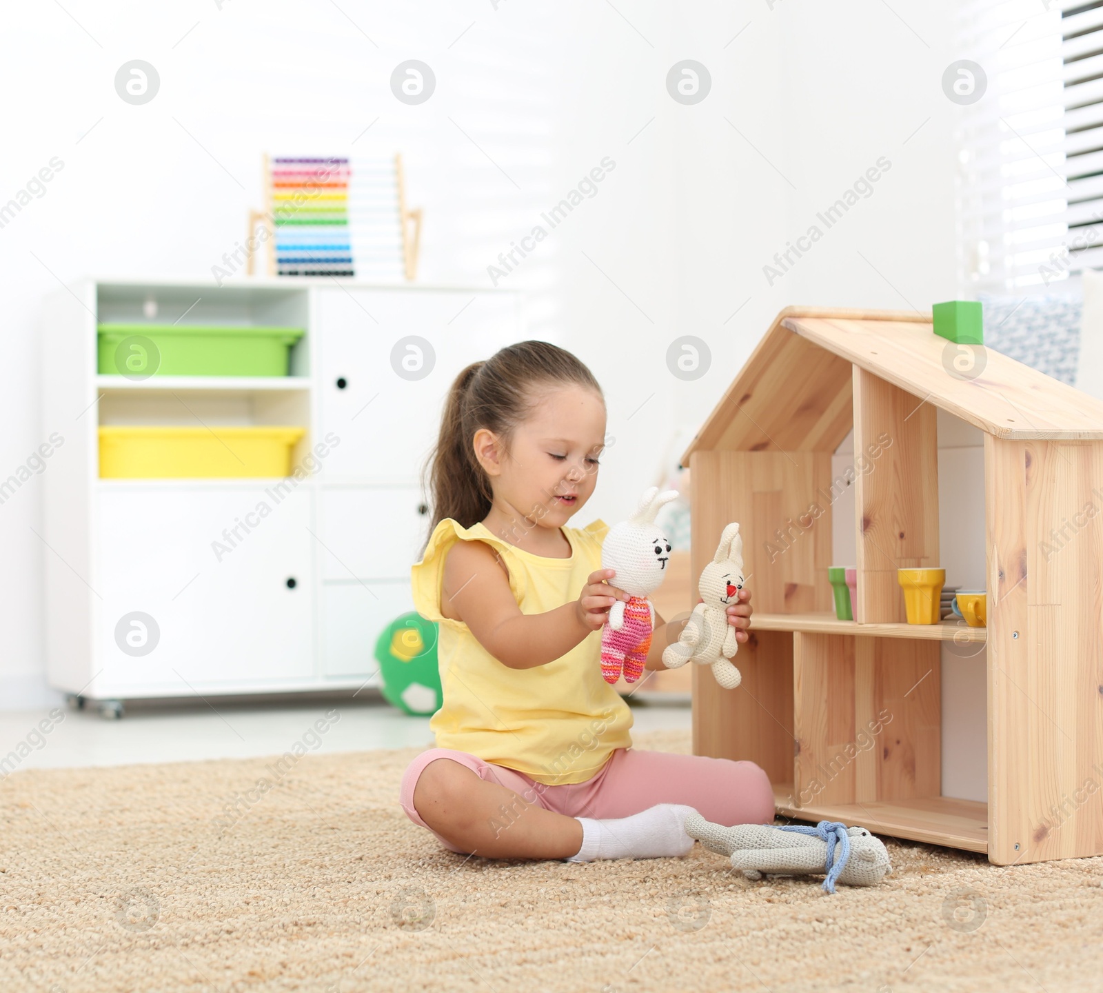 Photo of Cute little playing with toys near wooden house on floor at home, space for text