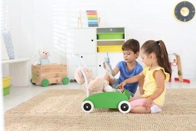 Photo of Cute little children playing with toy walker at home