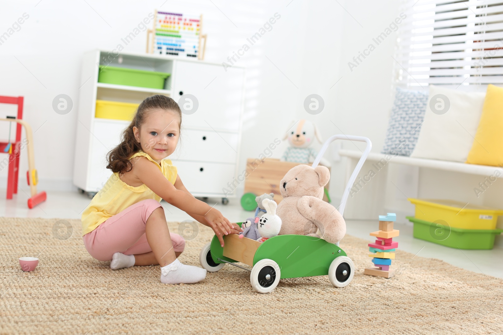 Photo of Cute little girl playing with toys on floor at home