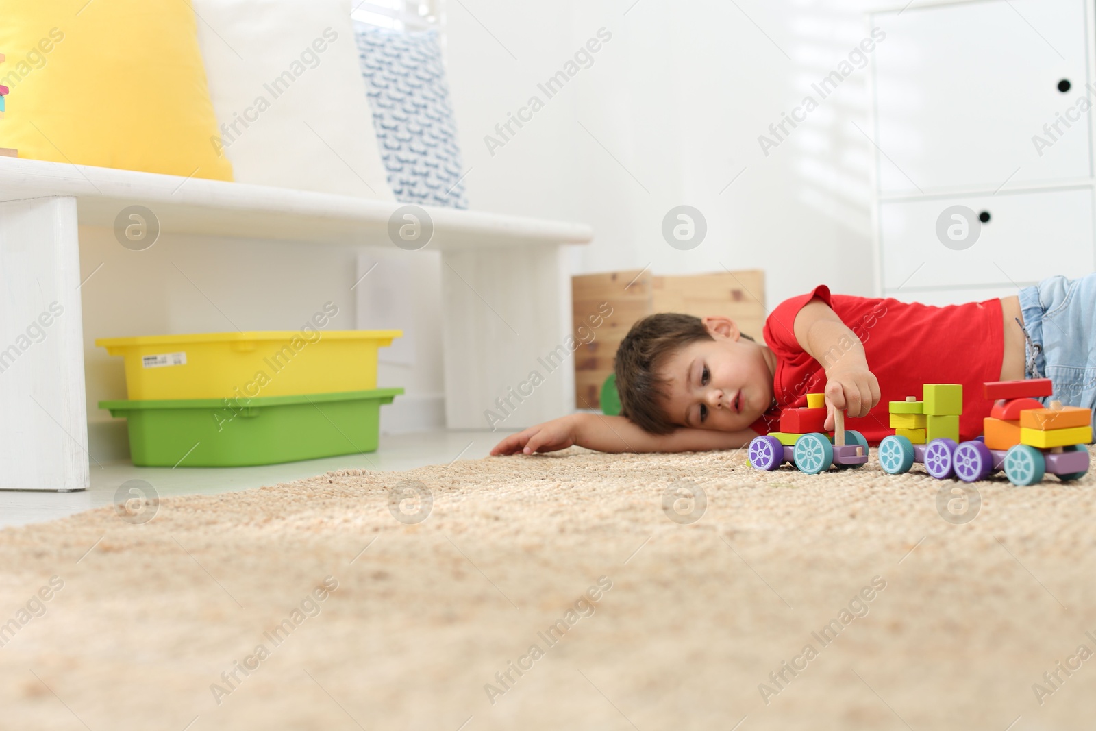 Photo of Cute little boy playing with colorful toys on floor at home, space for text