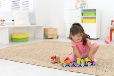 Photo of Cute little girl playing with toys on floor at home, space for text