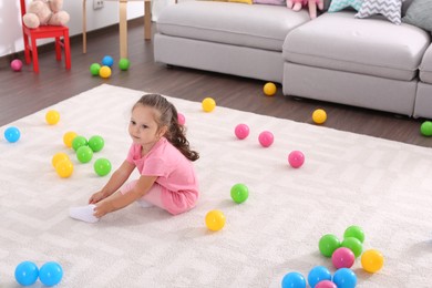 Photo of Cute little girl playing with toys on floor at home