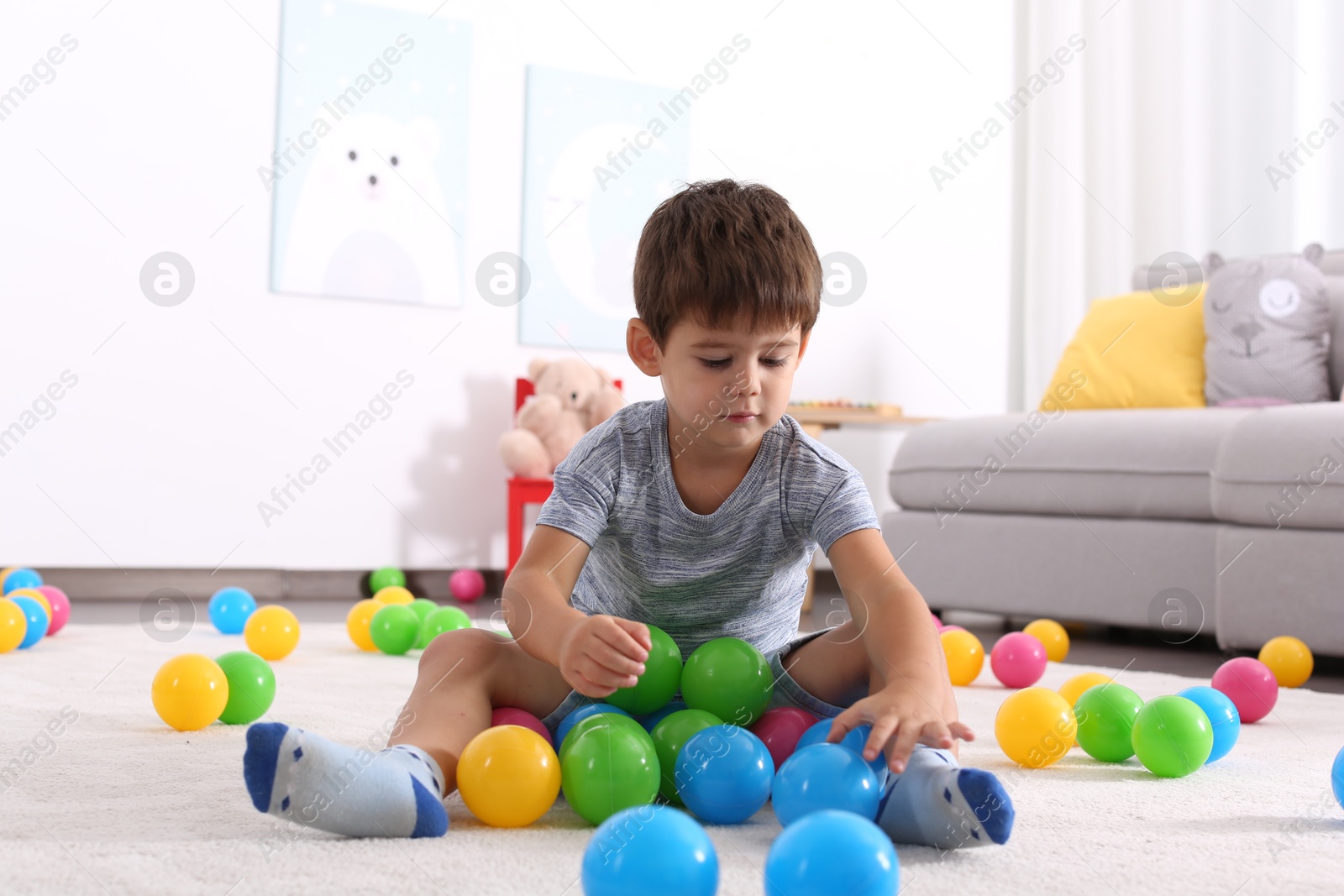 Photo of Cute little boy playing with toys on floor at home