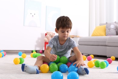 Photo of Cute little boy playing with toys on floor at home