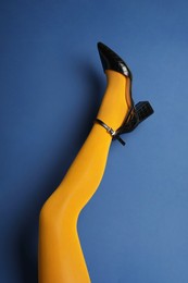 Photo of Woman wearing bright tights and high heel shoe on blue background, closeup