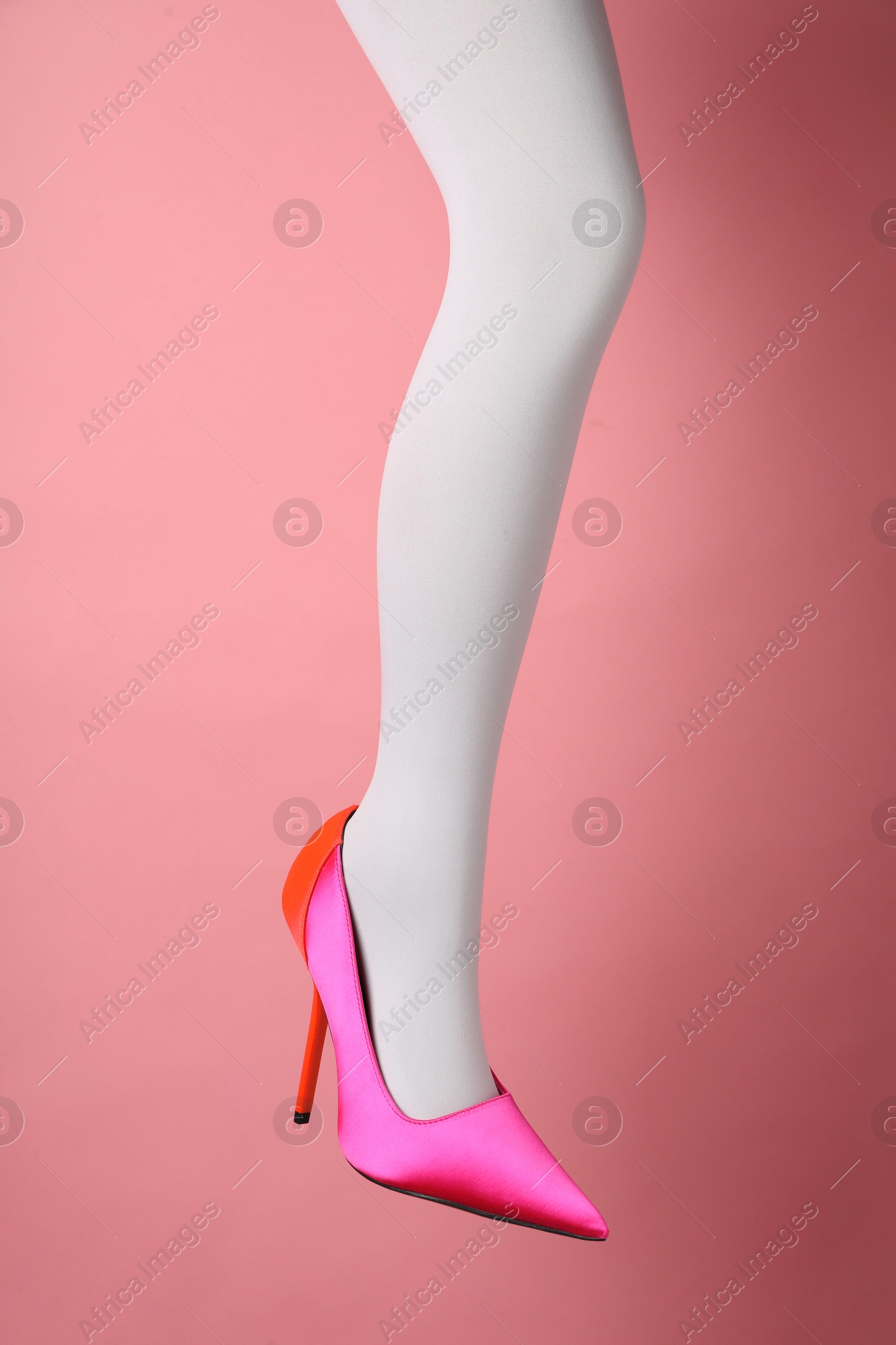 Photo of Woman wearing white tights and high heel shoe on pink background, closeup