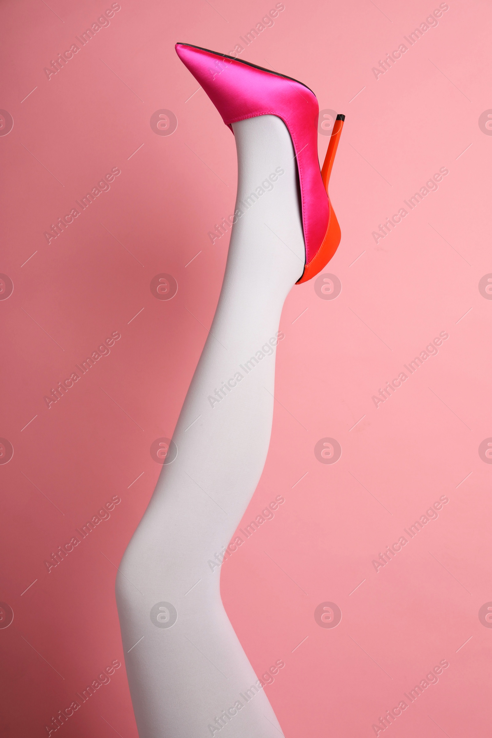 Photo of Woman wearing white tights and high heel shoe on pink background, closeup