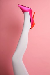 Photo of Woman wearing white tights and high heel shoe on pink background, closeup